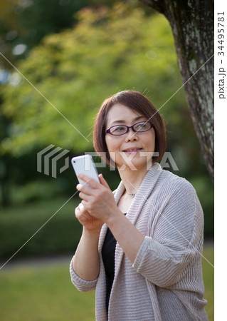 スマホ操作するメガネをかけたミドルの女性 34495781