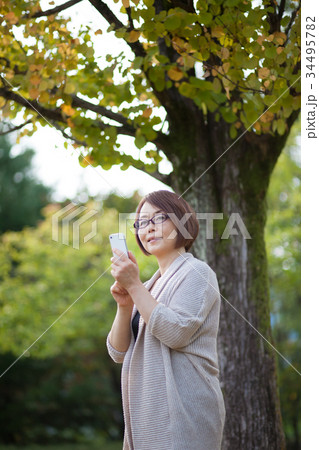 スマホ操作するメガネをかけたミドルの女性 34495782