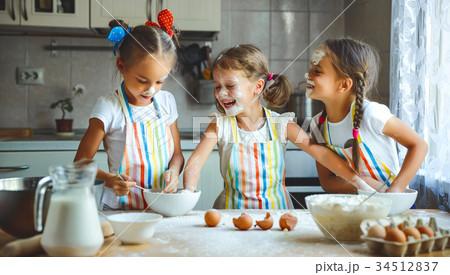 happy sisters children girls bake cookies, knead dough, play wit 34512837