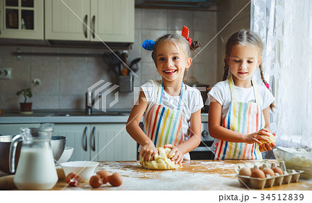 happy sisters children girls bake cookies, knead dough, play wit 34512839