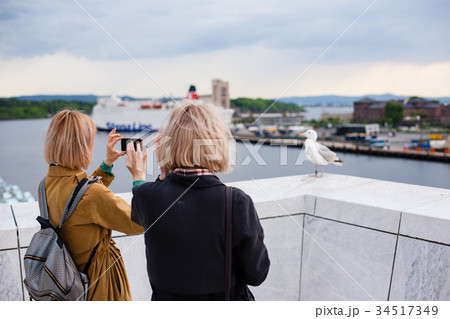 Two young stylish girls take pictures of a bird 34517349