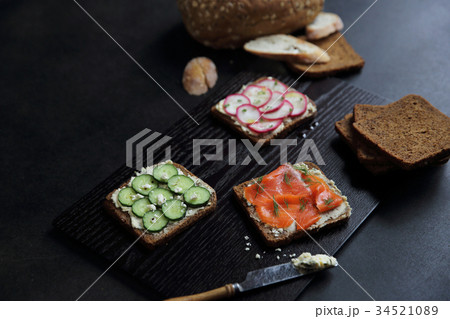 Sandwich with cereals bread smoked salmon beetroot and cucumber on dark marble background 34521089