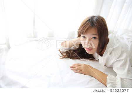 Asian young woman wake up with pillow in white room Asian young woman wake up with pillow in white room 34522077