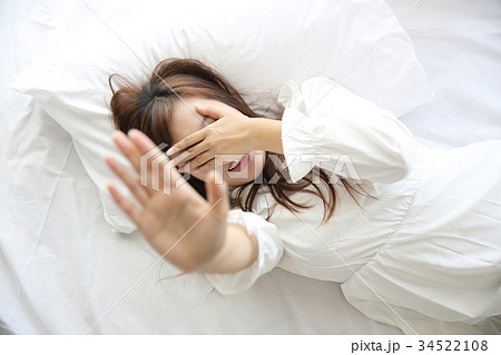 Asian young woman wake up with pillow in white room Asian young woman wake up with pillow in white room 34522108