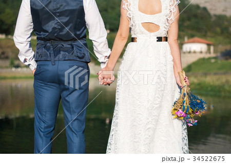 Wedding couple holding hands in front of a lake 34522675