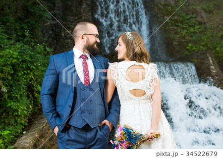 Wedding couple standing in front of a waterfall 34522679