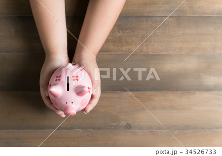 kid hold a pig bank on the vintage wood background 34526733