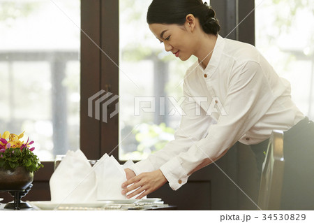 The staff is checking the napkin on the table. The staff is checking the napkin on the table. 34530829