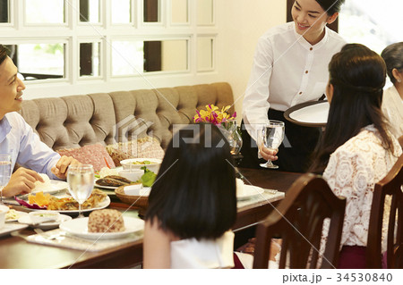 The waitress is serving water for the customer. 34530840
