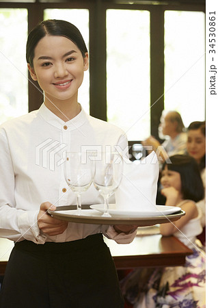the happy staff with the tray on hands is bringing glasses for customer. the happy staff with the tray on hands is bringing glasses for customer. 34530861