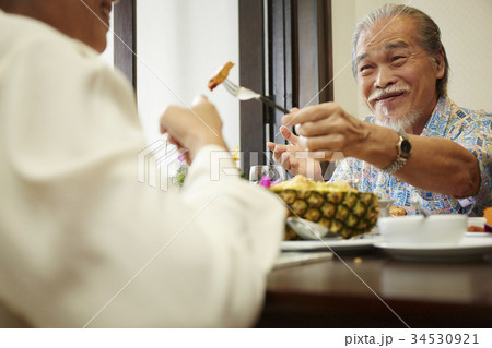 a senior man is smiling and feeding food to his wife a senior man is smiling and feeding food to his wife 34530921