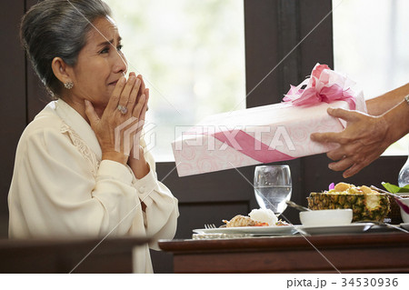 a senior woman is very happy with a gift box in the restaurant a senior woman is very happy with a gift box in the restaurant 34530936
