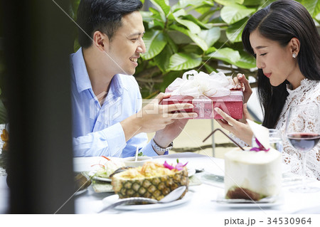 romantic boyfriend is giving a present to his girlfriend in restaurant romantic boyfriend is giving a present to his girlfriend in restaurant 34530964