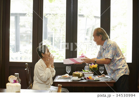 an old woman is surprised when seeing a present from her husband in restaurant 34530994