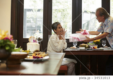 an old woman is surprised when her husband is giving a gift box to her an old woman is surprised when her husband is giving a gift box to her 34531013