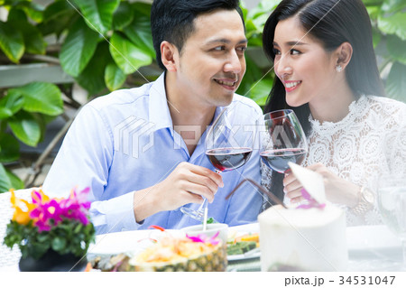 a young couple is looking each other and smiling when drinking wine in a restaurant 34531047