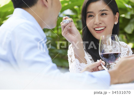 A young man is being feeded by his girlfriend at a lunch date. 34531070