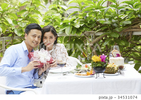 An Asian couple is holding a gift when dating at a restaurant. An Asian couple is holding a gift when dating at a restaurant. 34531074