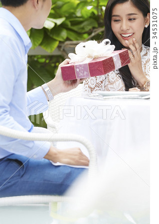 An young woman is surprised when his boyfriend gives her a gift. An young woman is surprised when his boyfriend gives her a gift. 34531075