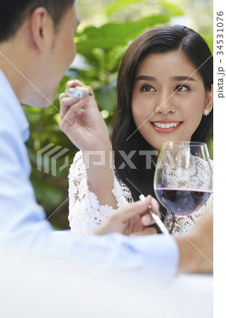 A woman is smiling and letting his boyfriend try eating her food. 34531076