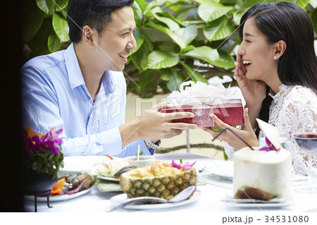 An Asian woman is feeling shy when her boyfriend is giving her a gift. An Asian woman is feeling shy when her boyfriend is giving her a gift. 34531080