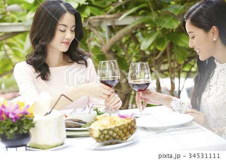 Two young women are smiling and holding wine glasses in a restaurant. Two young women are smiling and holding wine glasses in a restaurant. 34531111