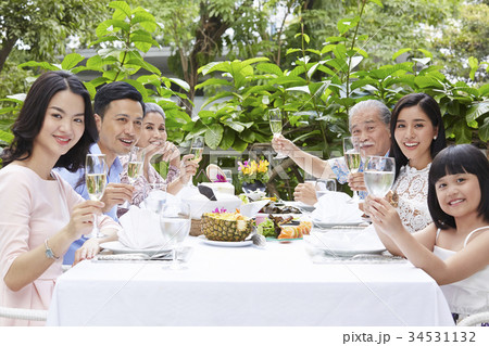 Extended family, parents, grandparents and child, eating outdoors 34531132