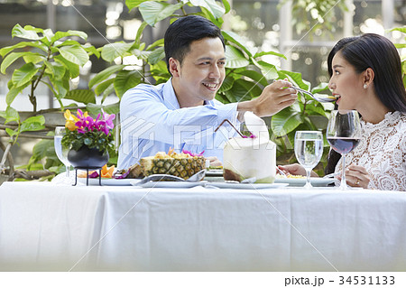 The couple is sitting and feeding each other at a restaurant The couple is sitting and feeding each other at a restaurant 34531133