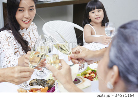 The family is sitting at a dining table and holding glasses of wine 34531164