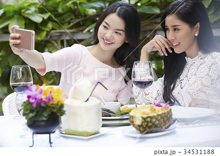 two beautiful ladies are taking selfie together in the banquet outdoors 34531188