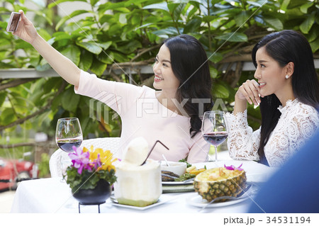 a lovely girl and friend are looking at her phone, smiling and taking selfie a lovely girl and friend are looking at her phone, smiling and taking selfie 34531194