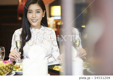 a good-looking woman is holding glass of wine and smiling in the dining room 34531209
