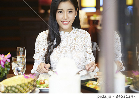 a woman with floral shirt is smiling and eating in a luxurious restaurant a woman with floral shirt is smiling and eating in a luxurious restaurant 34531247