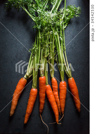 Fresh carrots with tops on a gray stone Fresh carrots with tops on a gray stone 34542530