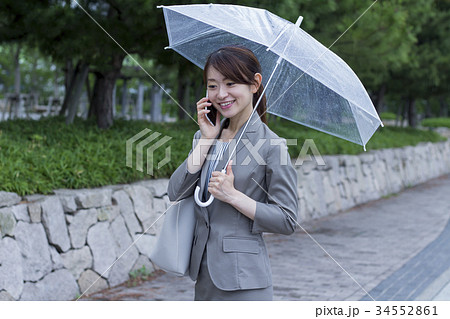 ビニール傘をさすビジネスウーマンの写真素材