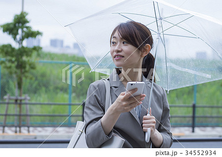 ビニール傘をさすビジネスウーマンの写真素材