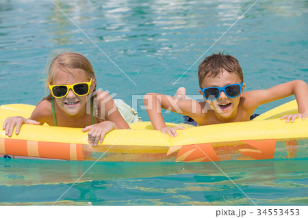Two happy children playing on the swimming pool at the day time. Two happy children playing on the swimming pool at the day time. 34553453