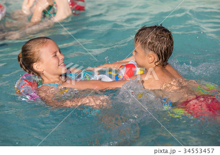 Two happy children playing on the swimming pool at the day time. 34553457