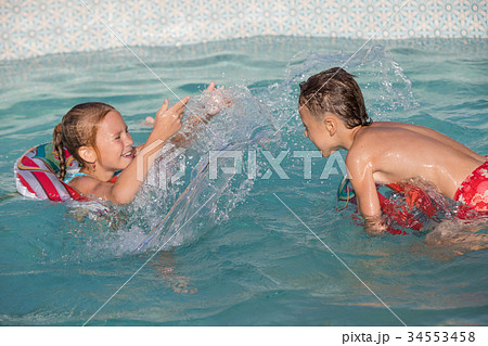 Two happy children playing on the swimming pool at the day time. 34553458