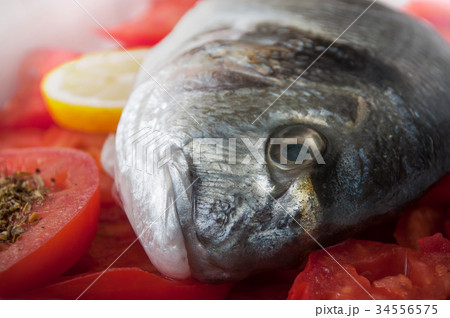 raw bream with tomatoes and lemon in a dish raw bream with tomatoes and lemon in a dish 34556575