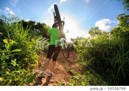 cyclist carrying mountain bike on forest trail cyclist carrying mountain bike on forest trail 34556796