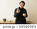 カップを持ちスマホを操作する60代男性 34560363