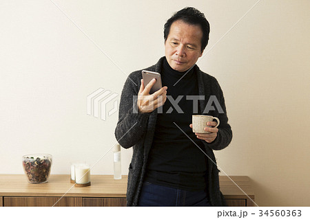 カップを持ちスマホを操作する60代男性 34560363