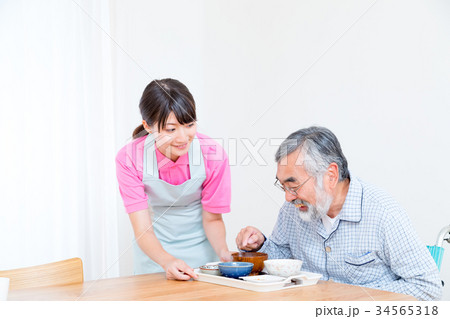 食事　若い看護師もしくは介護士とおじいちゃん　老人ホーム　デイケアセンター 34565318