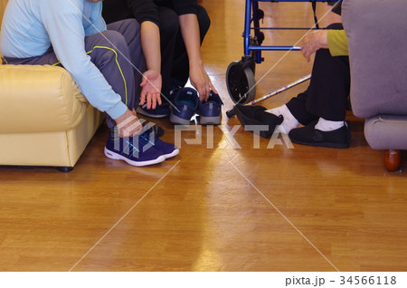 デイケア施設で靴を履き替える利用者とデイケアスタッフ デイケア施設で靴を履き替える利用者とデイケアスタッフ 34566118