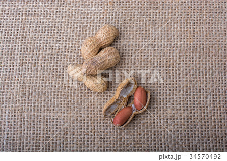 Cracked open peanuts with shell on a linen canvas Cracked open peanuts with shell on a linen canvas 34570492