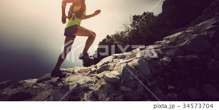 woman trail runner running up top of mountain 34573704