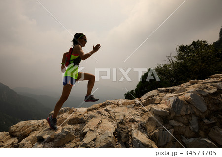 woman trail runner running up top of mountain 34573705