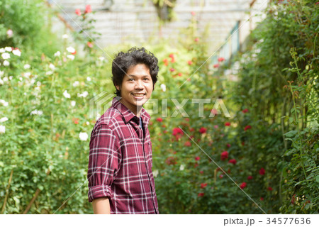 Asian man gardener standing at rose flower garden 34577636