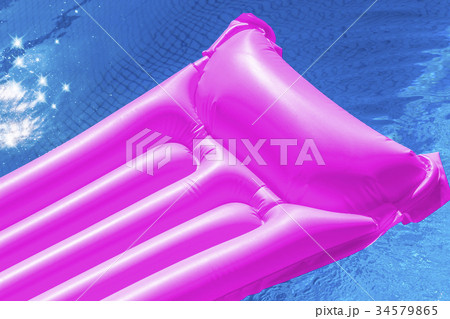 Pink air mattress floating in a swimming pool. 34579865